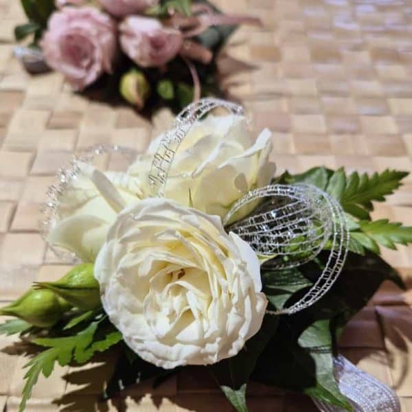 corsage 1 Beautiful white wedding flower arrangement with roses and greenery, perfect for special occasions.