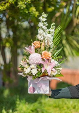 pastel posy box Vibrant floral arrangement with lilies, roses, and chrysanthemums in a pink wrapping, perfect for special occasions.