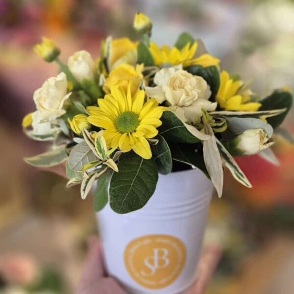 Elegant flower arrangement with yellow blooms and lush greenery, suitable for special occasions.