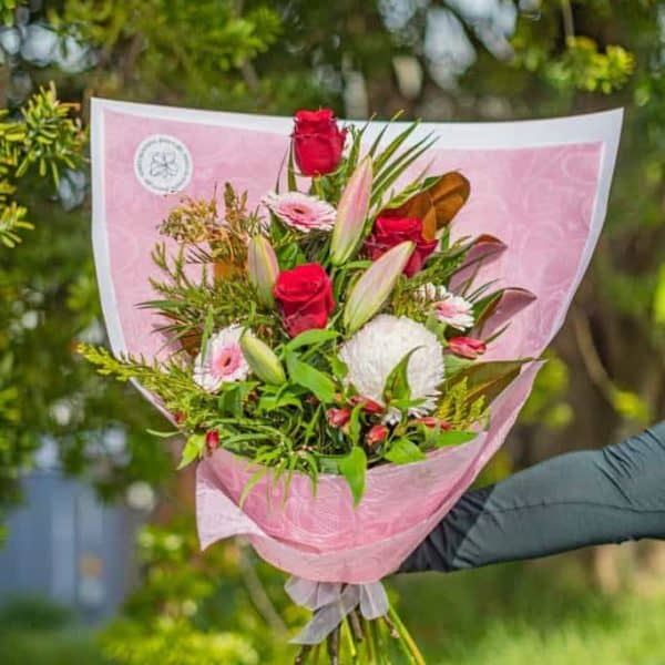 Colourful fresh flower bouquet with roses, lilies, and greenery, wrapped in pink paper, perfect for celebrations or gifting.