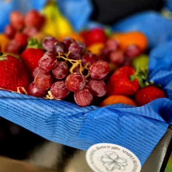 Colorful fresh fruits including strawberries and grapes in a blue wrapping for healthy snacking or gift-giving.