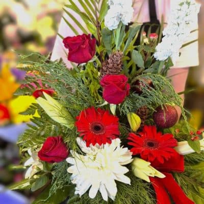 Vibrant floral arrangement with red roses, gerbera daisies, white chrysanthemums, and lush greenery, perfect for gifting or home decor.