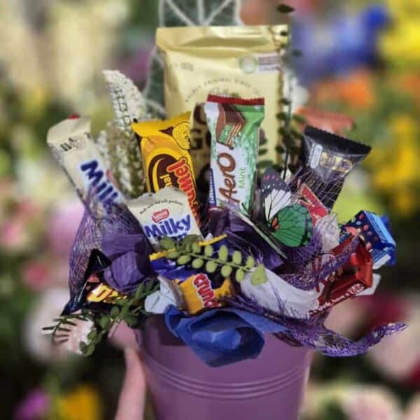 Colourful chocolate gift bouquet with assorted chocolates, greenery, and decorative wrapping.