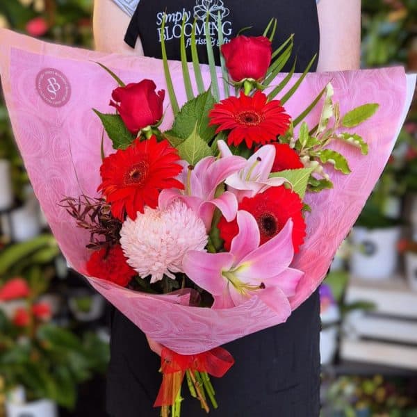 Vibrant mixed flower bouquet featuring pink lilies, red roses, gerbera daisies, and greenery from Simply Blooming florist.