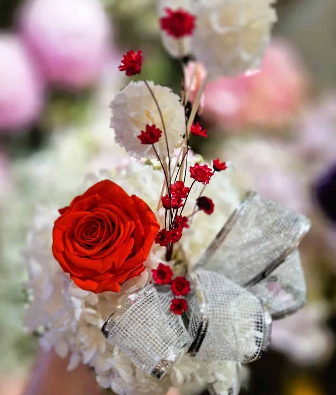 Beautiful bouquet featuring vibrant roses and soft white flowers with a decorative bow.