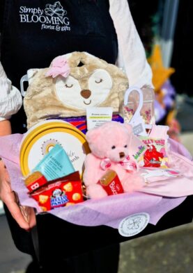 Simply Blooming Gift Basket Cute plush bear with floral-themed gifts and treats.
