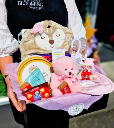 Simply Blooming Gift Basket Cute plush bear with floral-themed gifts and treats.