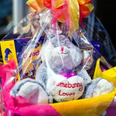 Easter gift basket with plush bunny, chocolates, and colorful ribbons.