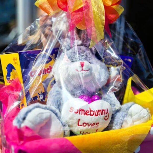 A festive Easter gift basket featuring a plush bunny, chocolates, and vibrant ribbons, perfect for celebrating spring and Easter.