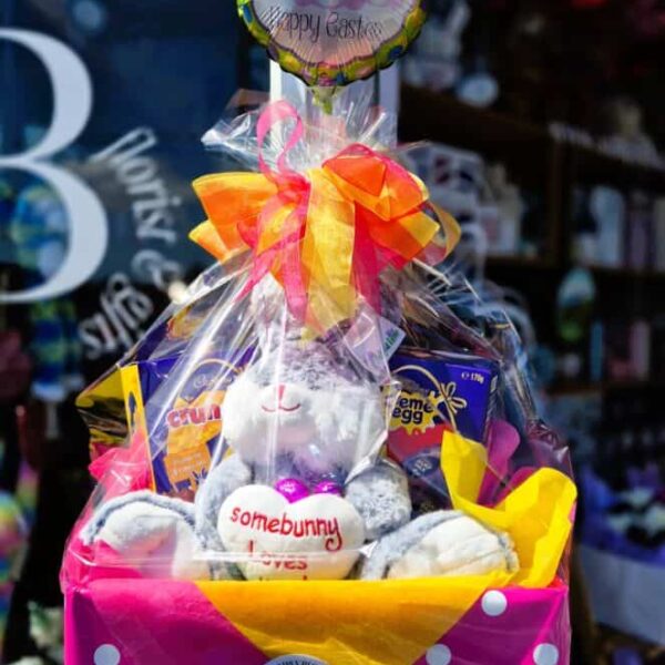 Festive Easter gift basket with plush bunnies, chocolates, and a decorative balloon, perfect for celebrating spring and Easter.