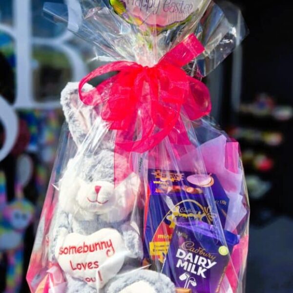 A festive Easter gift basket with a plush bunny, chocolate eggs, and a Dairy Milk bar, ideal for gifting during the Easter season.