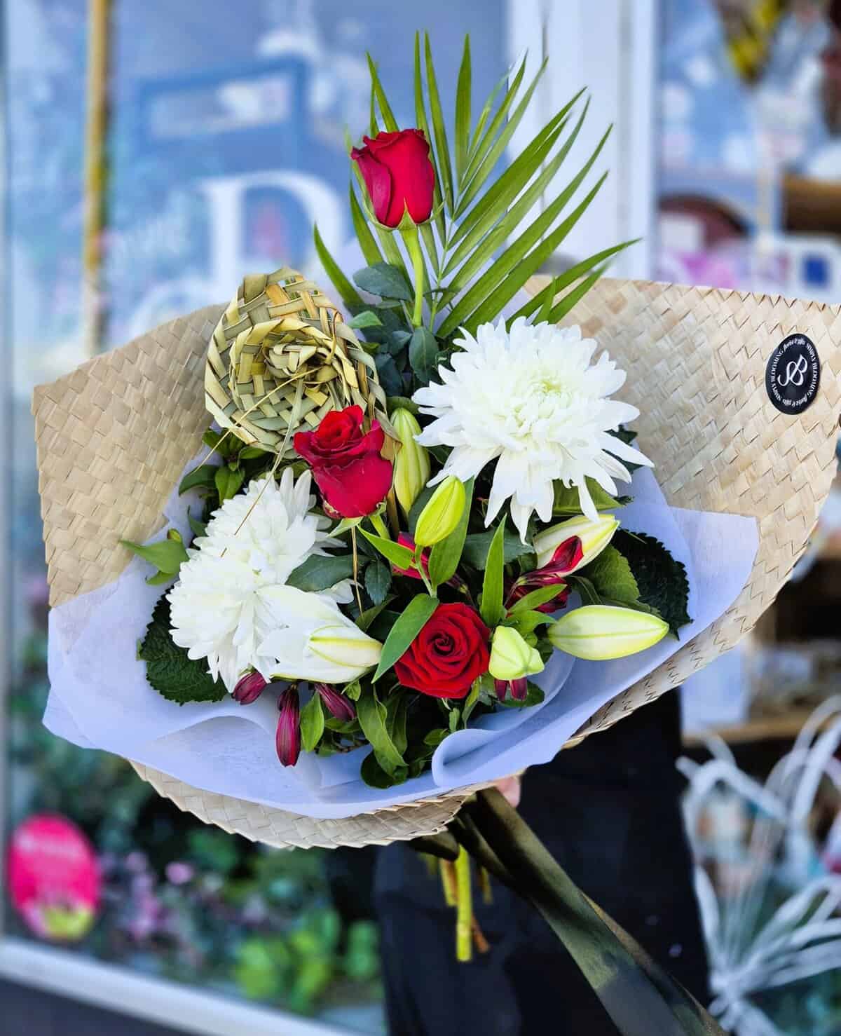 Beautiful flower arrangement with roses, lilies, and dahlias in a woven wrap.