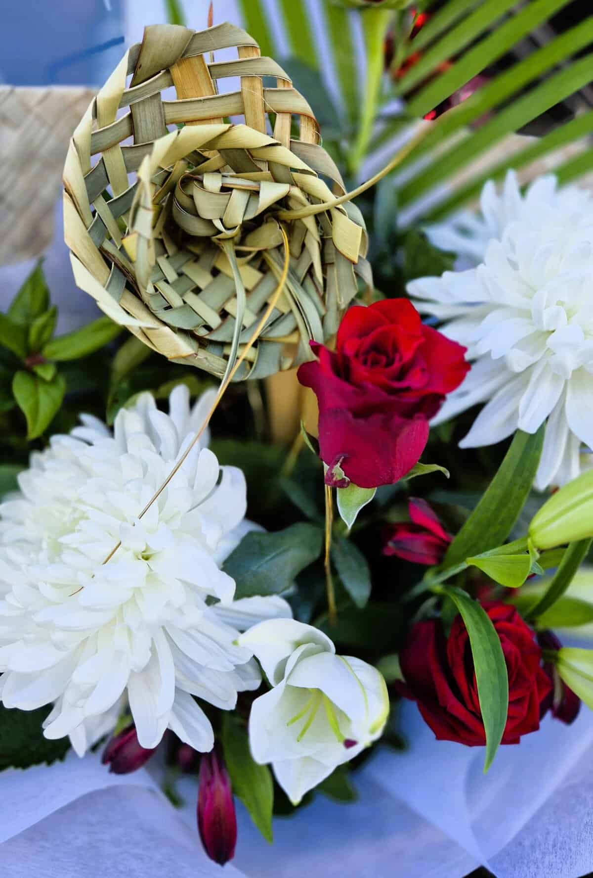 Beautiful floral display featuring red roses and white dahlias with a woven decorative element.