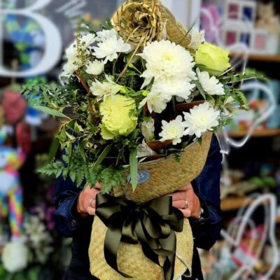 Beautiful white and green floral arrangement in a decorative wrapping with a black ribbon bow.