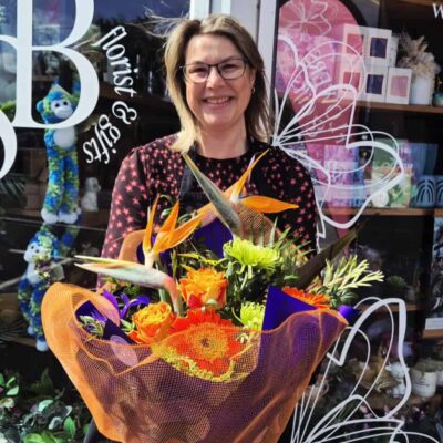 Bright floral bouquet with vibrant orange, yellow, and purple blooms.