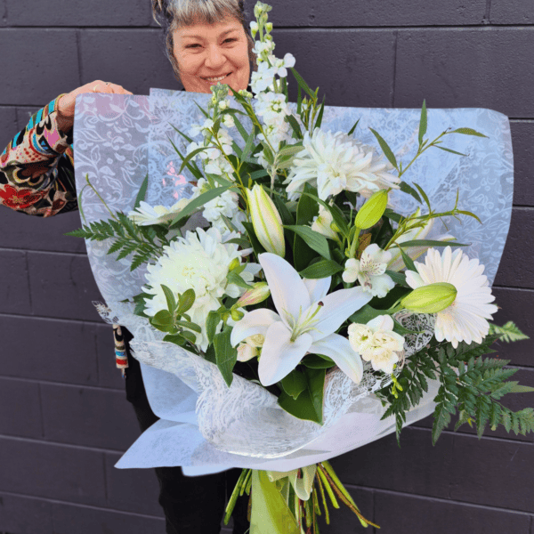 Beautiful white floral bouquet with lilies, daisies, and greenery.