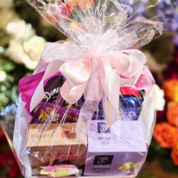 A beautifully wrapped gift basket featuring chocolates, candies, and sweet treats, ideal for celebrating special moments or as a thoughtful gift.