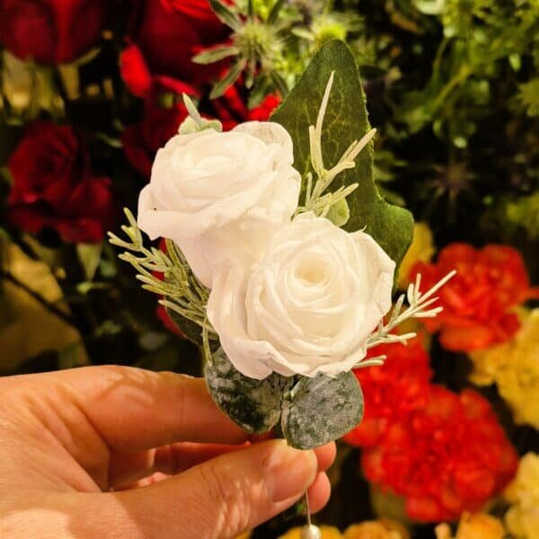 White floral boutonniere with greenery for wedding or special event.