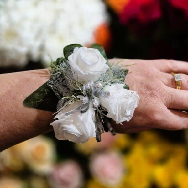 White rose wrist corsage with silver accents for special occasions.